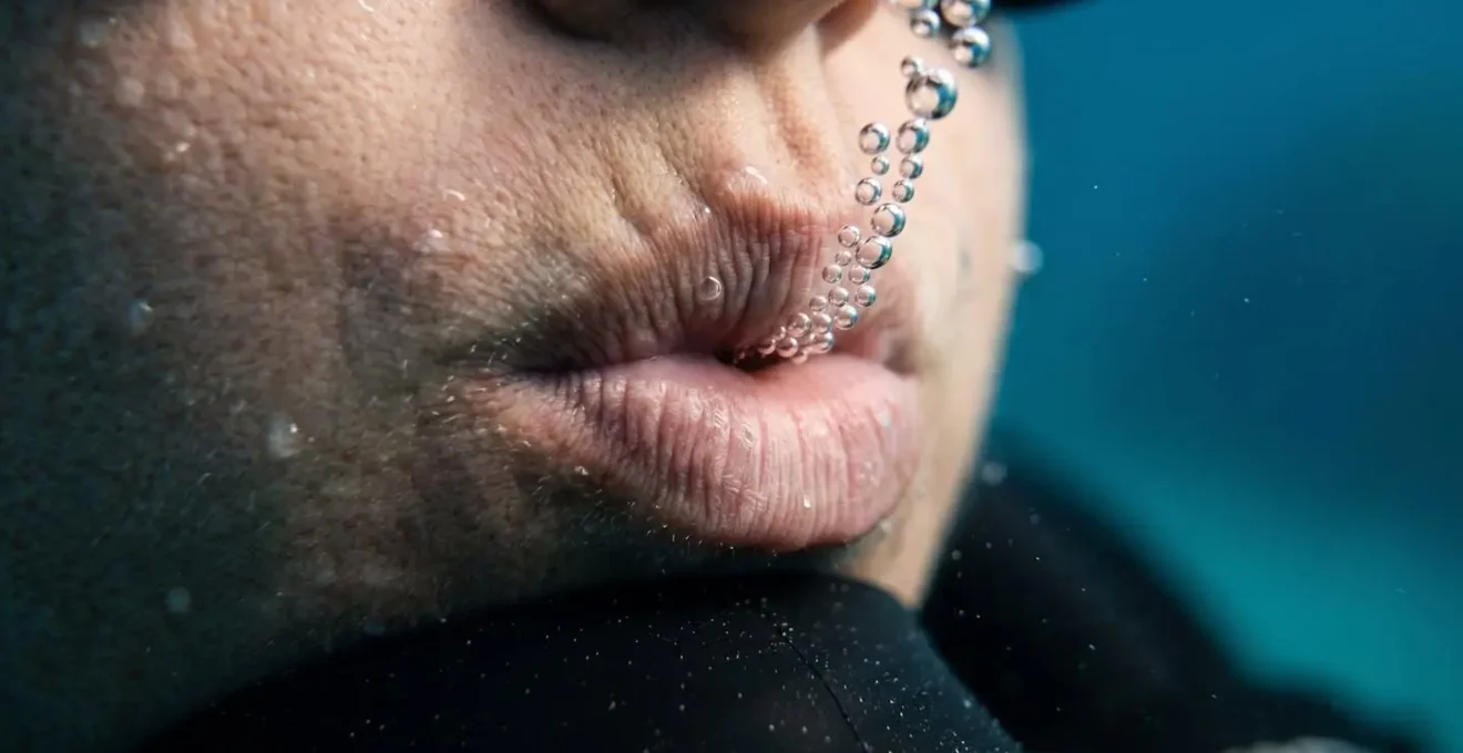 Gros plan macro sur les lèvres d'un plongeur pratiquant la technique de respiration sifflée sous l'eau