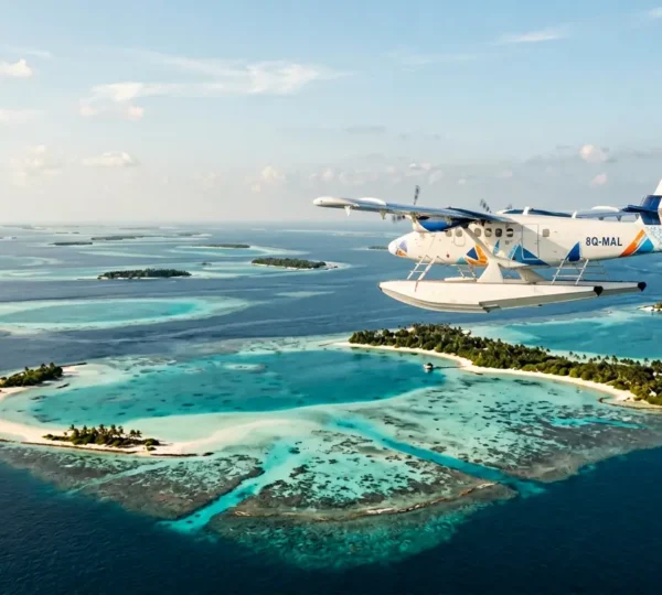 Vue aérienne d'un hydravion survolant les lagons turquoise des Maldives avec ses atolls en arrière-plan