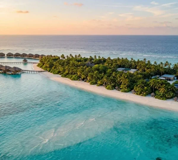 Vue aérienne d'une île resort aux Maldives montrant le contraste entre la zone touristique et les infrastructures techniques