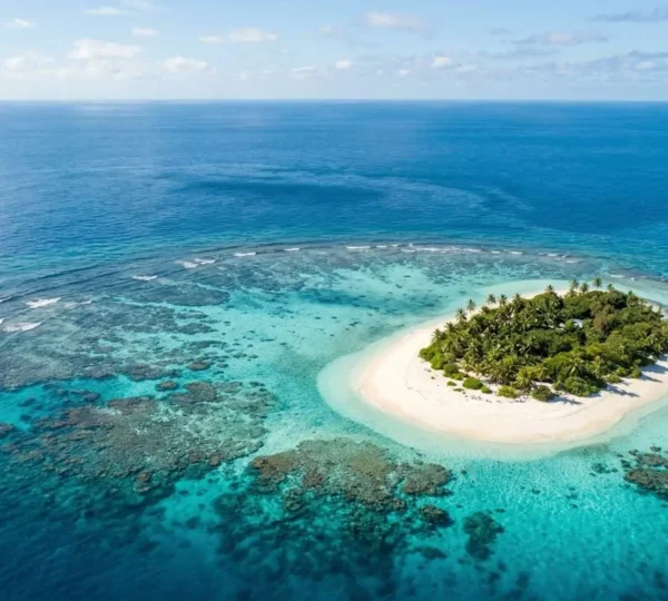 Vue aérienne d'une île tropicale entourée de récifs coralliens aux nuances turquoise et bleues profondes
