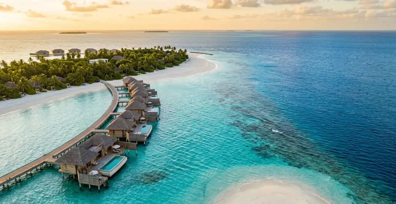 Vue aérienne d'un resort aux Maldives avec ses bungalows sur pilotis et ses eaux cristallines, illustrant le paradis tropical et son coût réel