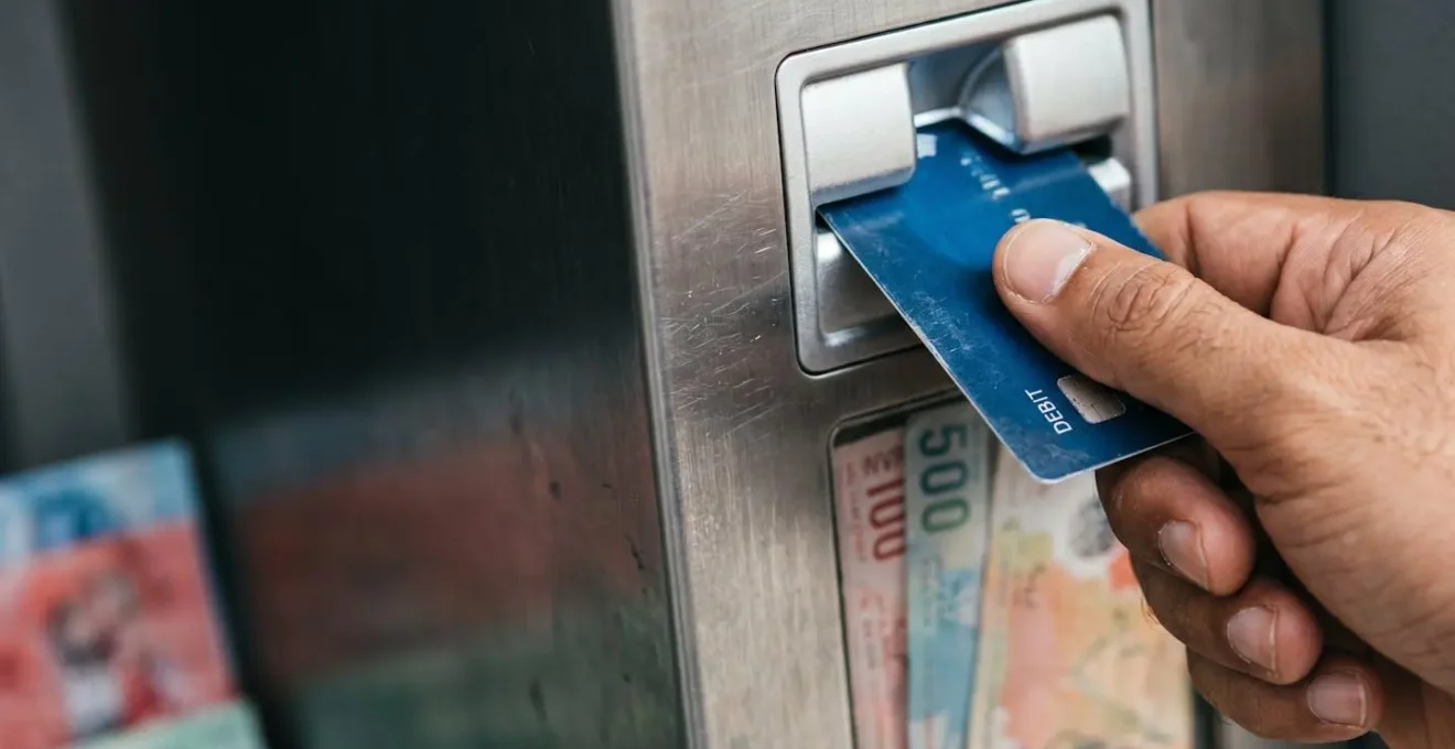 Main insérant une carte bancaire dans un distributeur, billets de rufiyaa flous en arrière-plan