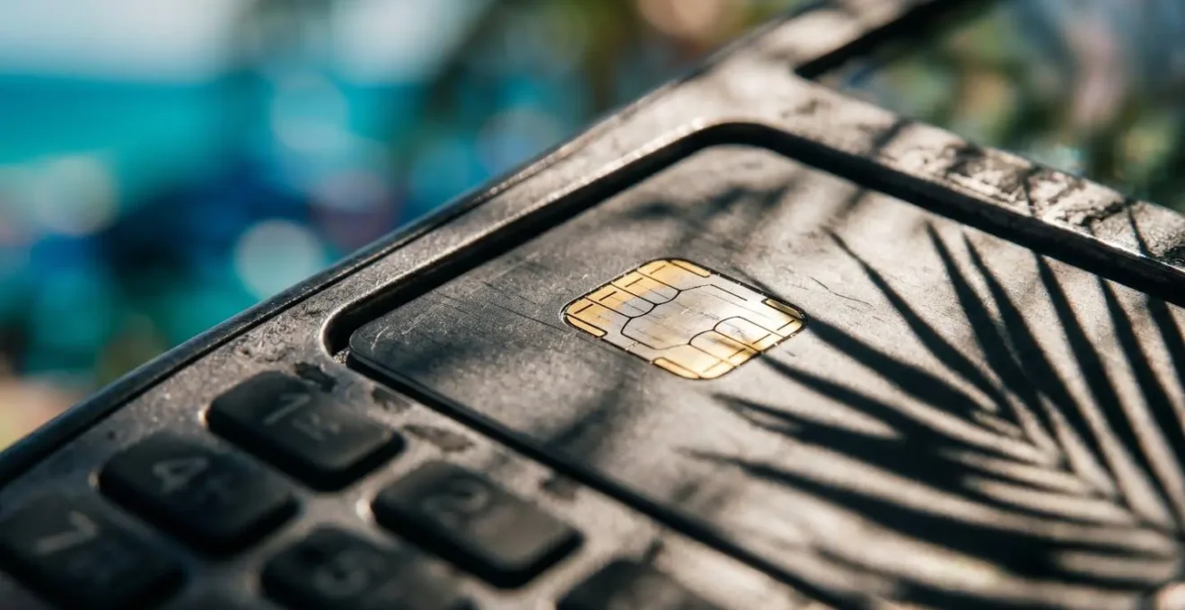Gros plan sur un terminal de paiement moderne avec carte bancaire, ambiance tropicale en arrière-plan flou