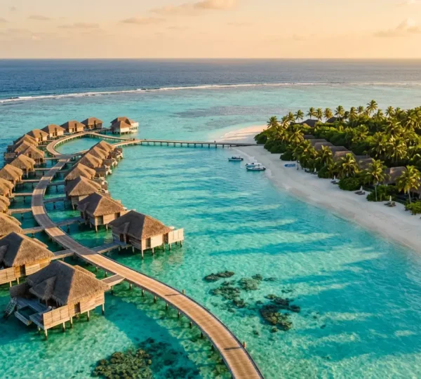 Vue aérienne d'un lagon turquoise avec villas sur pilotis et bungalows plage bordés de palmiers