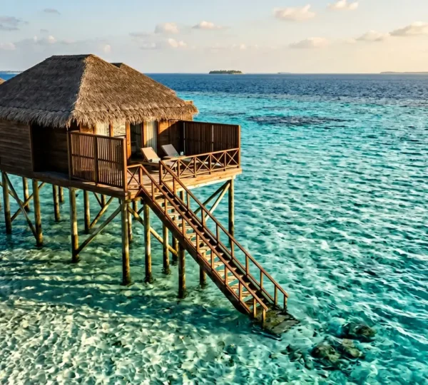 Vue aérienne d'une villa sur pilotis avec accès direct au lagon turquoise et escalier immergé